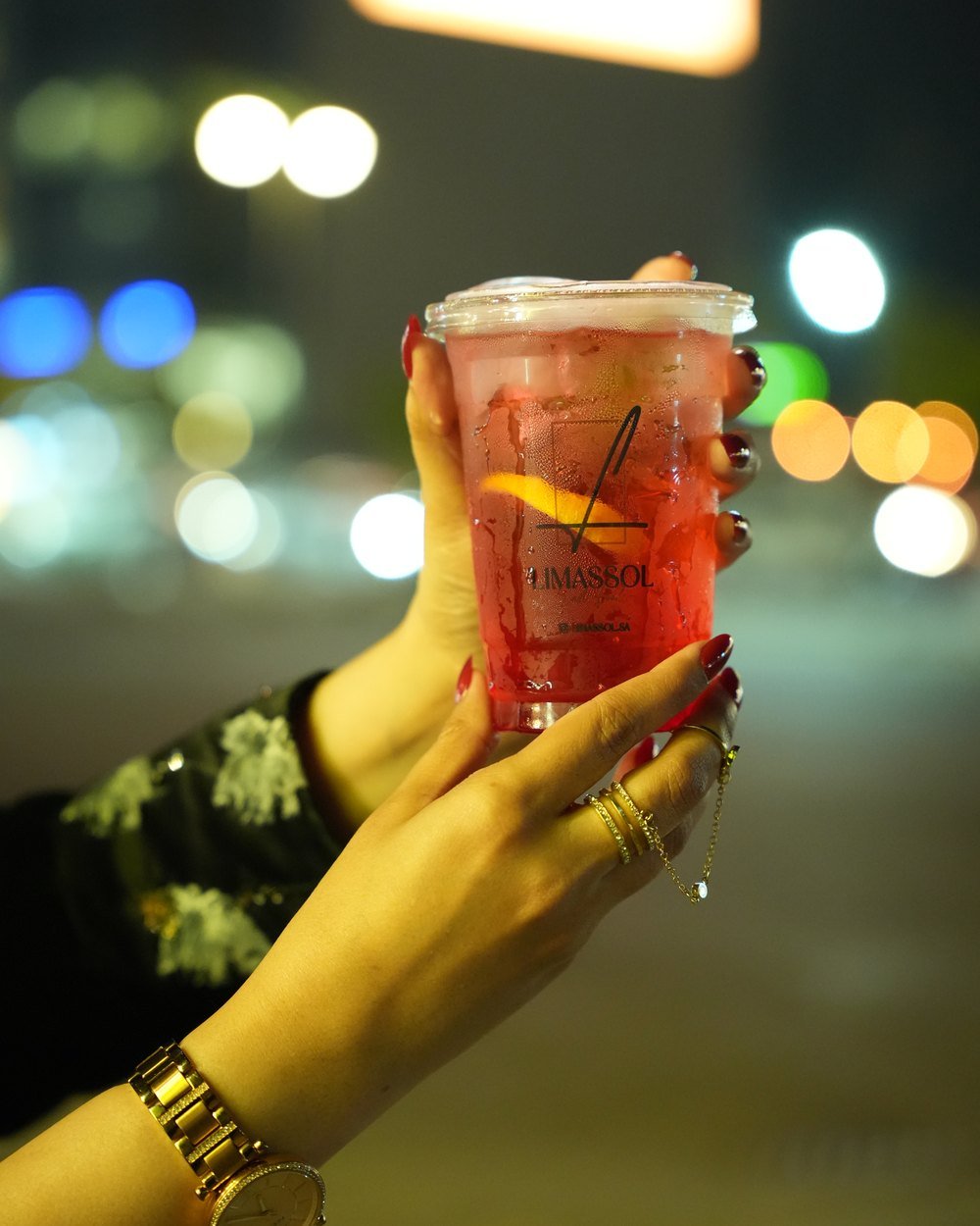 Iced drink held up against city bokeh at night