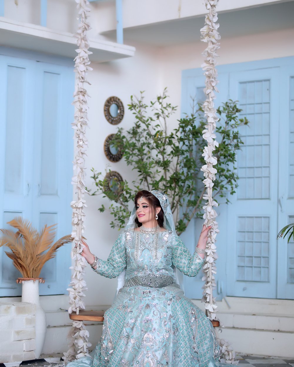 Bride seated on a floral swing in a turquoise gown